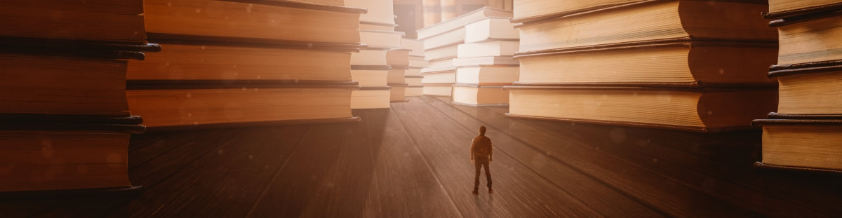 An author standing in front of stacks of giant books